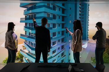 four persons standing infront of a virual building