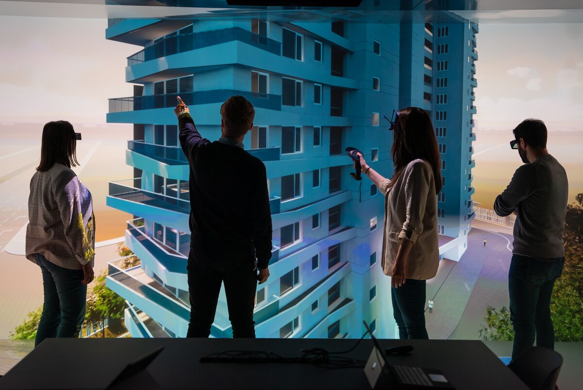 four persons standing infront of a virual building