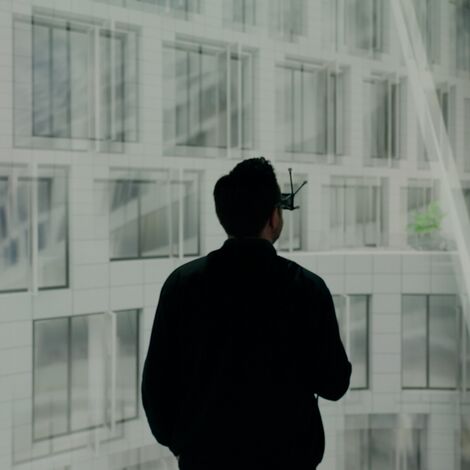 Man wearing VR-Glasses, standing infront of a window